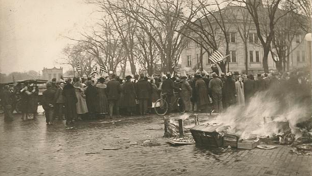 A crowd turns to a man waving an American flag.